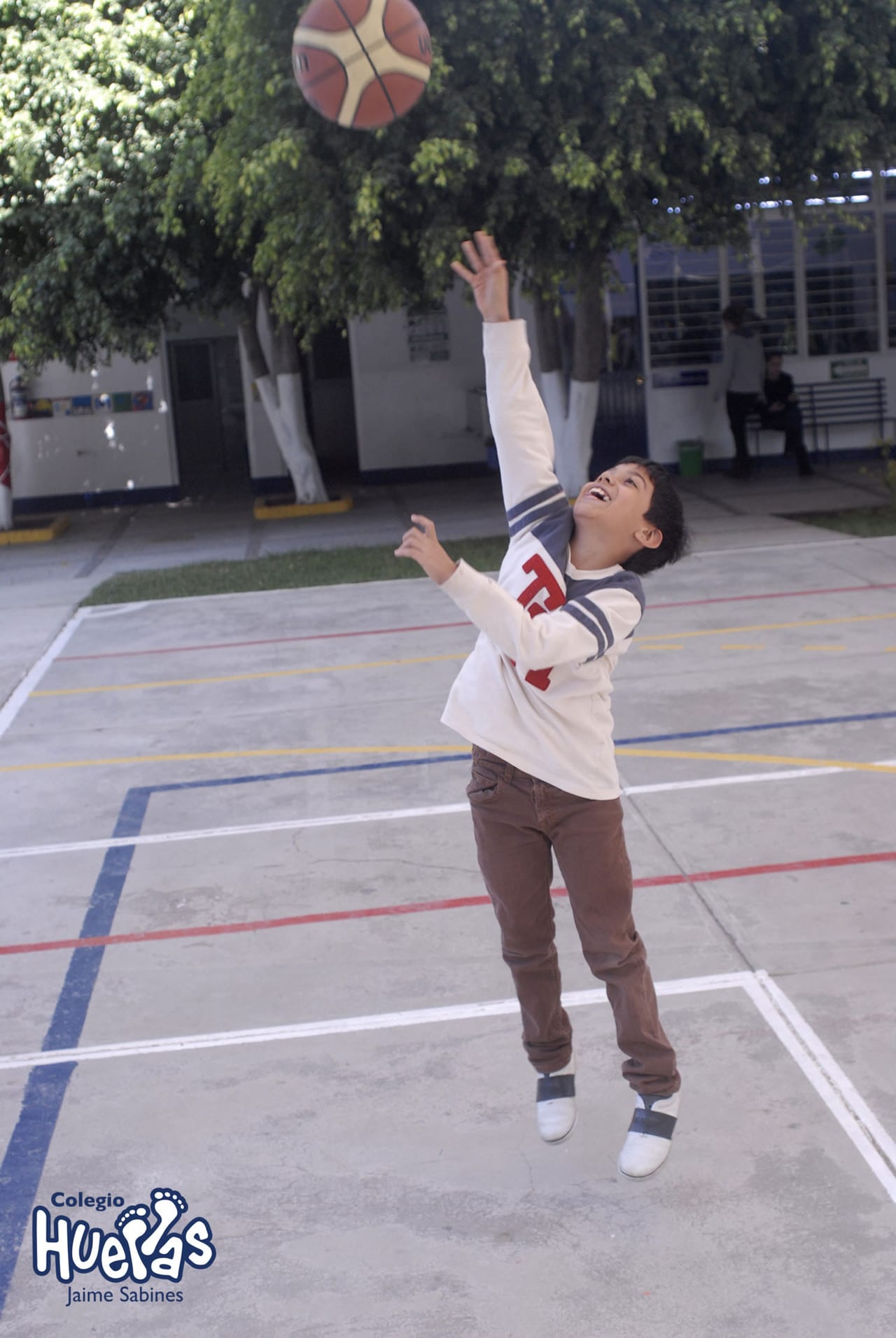 Niño lanza una pelota en la cancha de la escuela