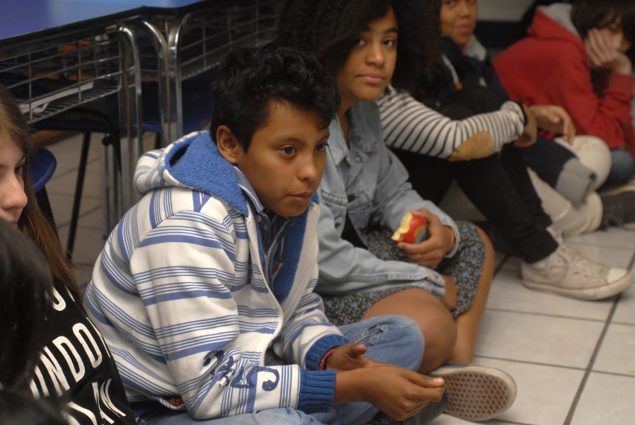 Alumnos de secundaria sentados en el piso durante una pausa