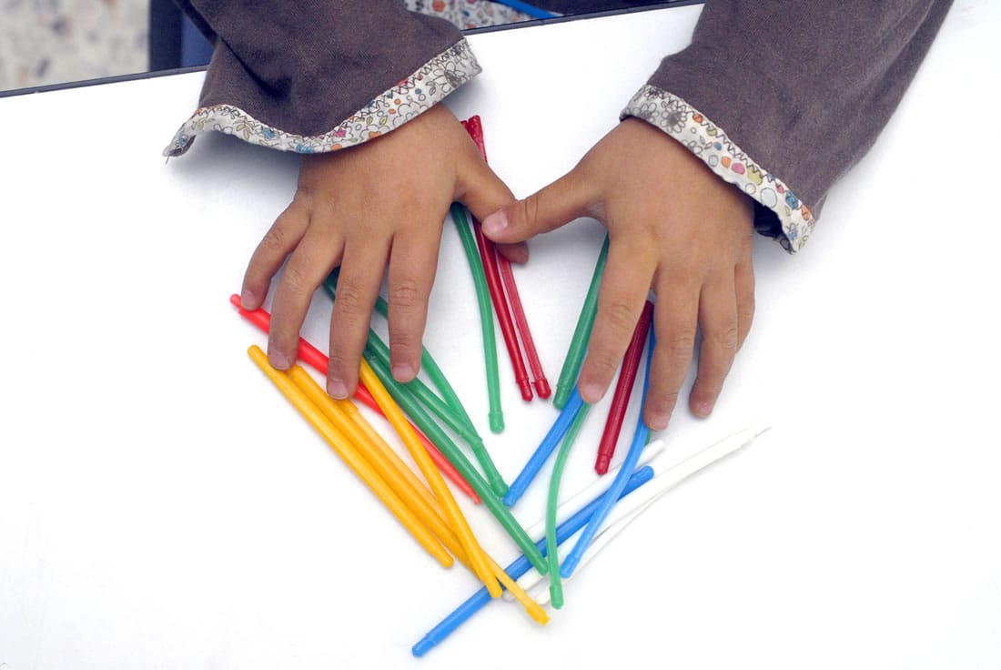 Manos de una niña forman una figura con popotes de colores